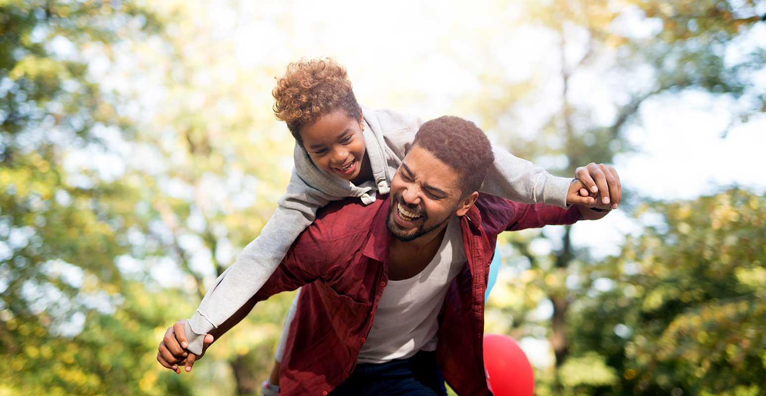 Man with child on his back in forest