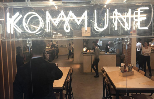 Picture of restaurant with a sign made of lights reading "KOMMUNE"