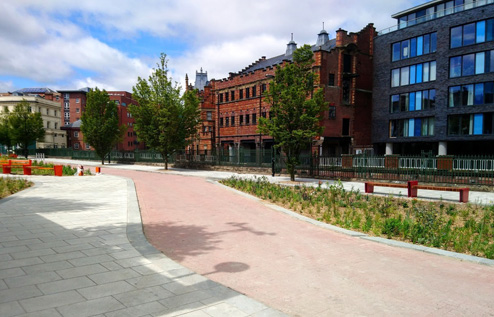 Picture of red pedestrian path with trees and buildings in the background