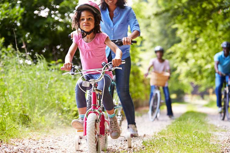 Girl riding bike with more cyclists behind on path