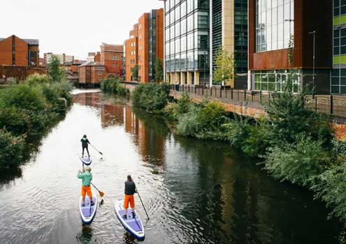 3 people on Stand Up Paddleboards on a river/canal 