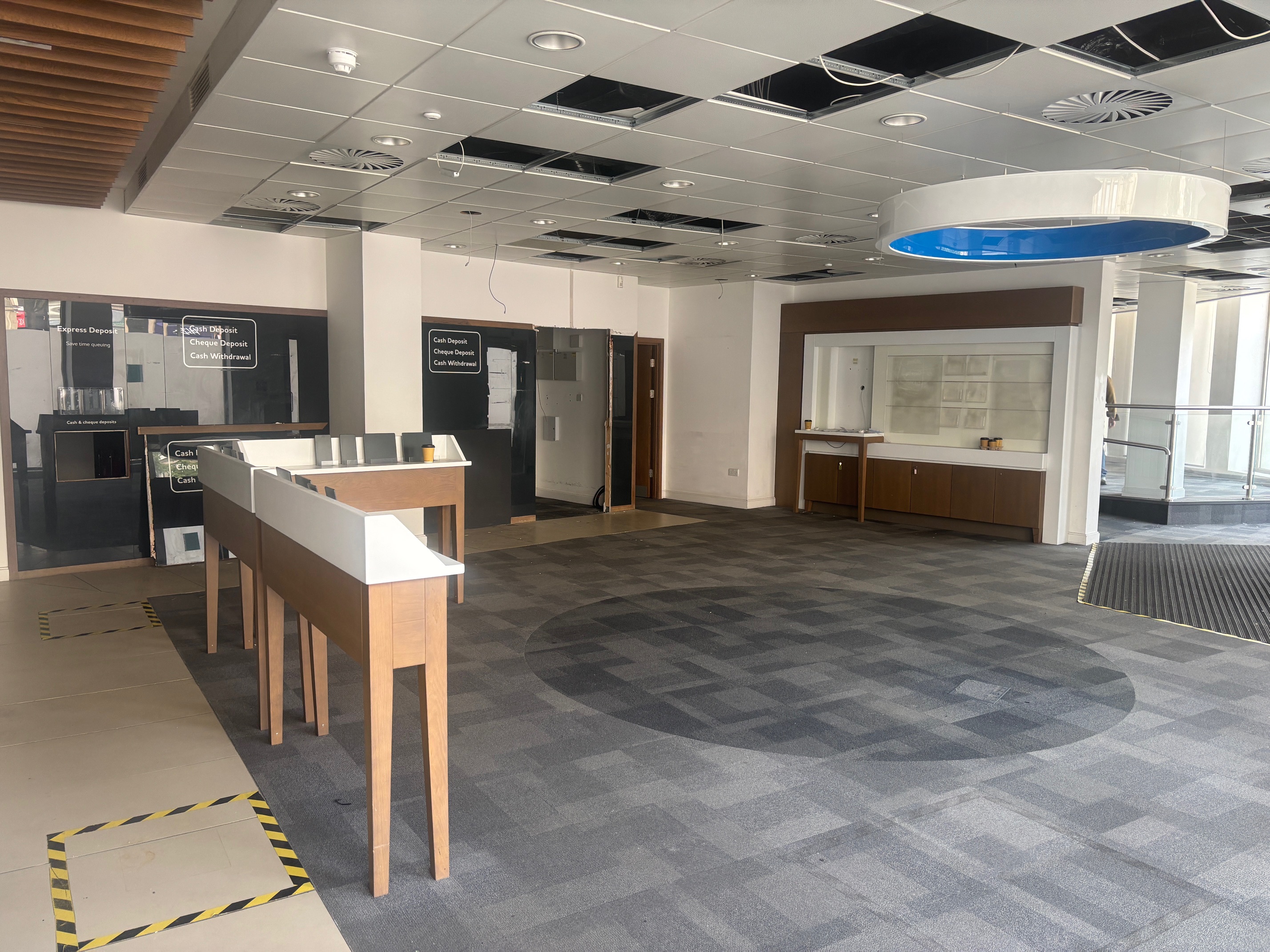 An interior shot of the former Yorkshire Bank building on Fargate. There are glass-fronted offices in the background, a large open space with grey carpet and some desk space people would have leant on to write is in the centre.