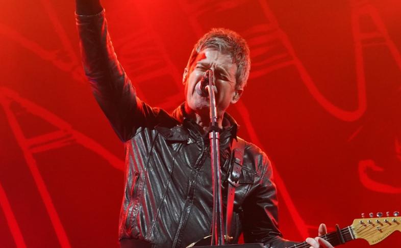 Noel Gallagher on stage with red lighting