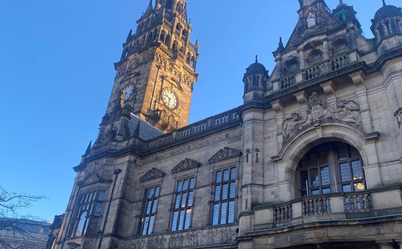Image of the front of the Town Hall showing the balcony and the clock tower under a blue sky