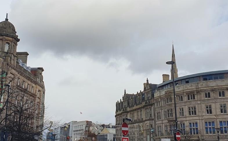 Top of Fargate showing tall buildings on either side. Its a dull day with clouds in the sky.