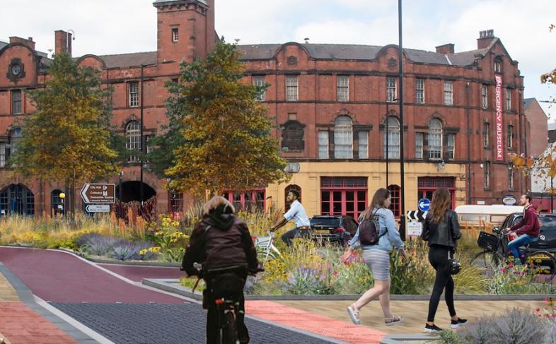 West Bar in Sheffield, with buildings in the background and people walk and cycling on paths with trees and grass around them