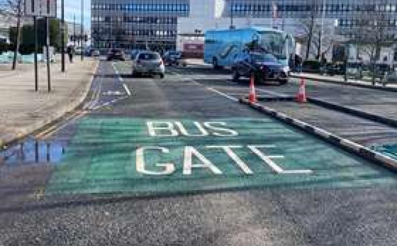 Painted words on Arundel Gate read 'bus gate', surrounded by green tarmac, to signal the point cars cannot pass or they receive a fine, as traffic drives past