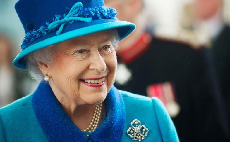 A smiling Queen Elizabeth the second wearing a blue hat and coat