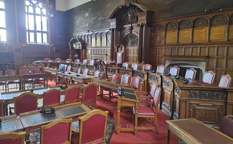 The Council Chamber at Sheffield Town Hall with the desks and chairs laid out ready for a meeting and light shining through the windows on a cloudy day