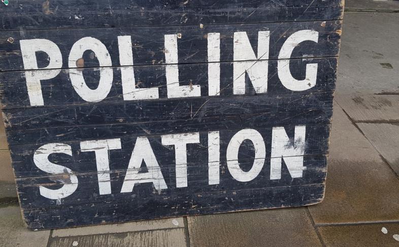 A blackboard sign with Polling Station written in white capital letters is propped up on the steps of Sheffield Town Hall
