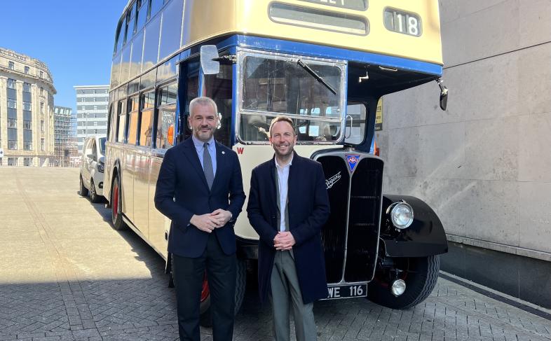 South Yorkshire Mayor Oliver Coppard and Cllr Ben Miskell stand in front of a vintage yellow and blue double decker bus