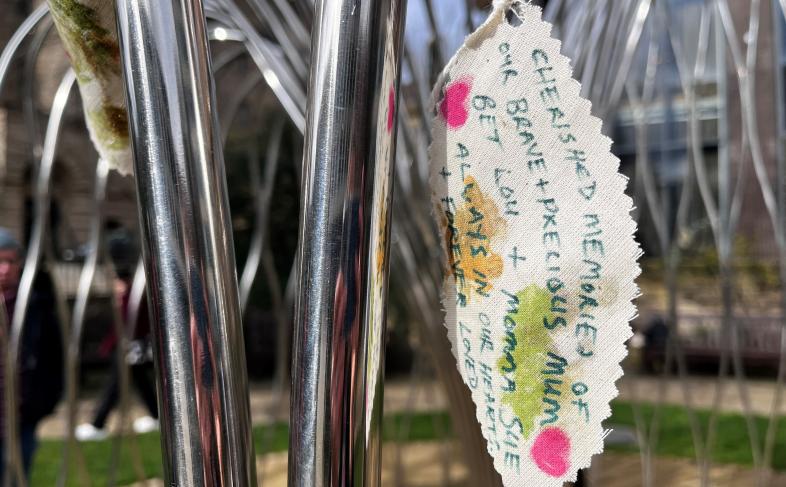 Part of steel frame of Covid memorial willow tree with a fabric colourful message leaf attached to it