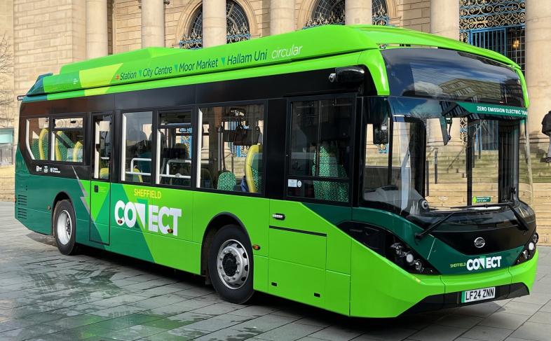 A green, fully electric, Sheffield Connect bus stands outside the front of the Sheffield City Hall