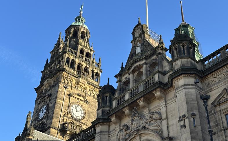 The Sheffield Town Hall clock tower and flagpole can be seen in the picture, which has been taken from street level looking up with a clear blue sky behind them