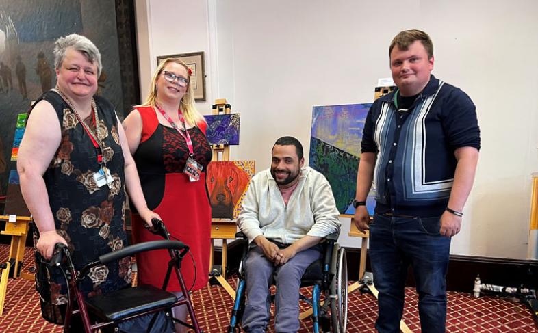 Four people in front of their artwork