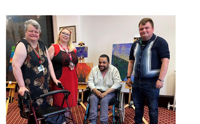 Attendees at Learning Disability Week launch in front of artwork