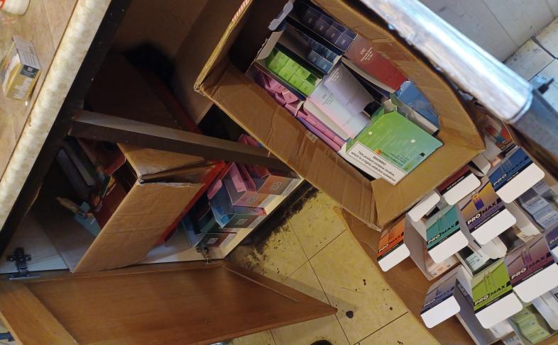 Image shows several boxes spilling out of a kitchen unit, each box contains illegal tobacco and vapes