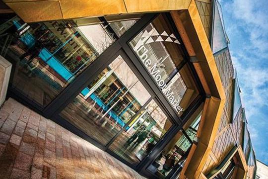 Image of the entrance to the Moor Market made of glass panels and a wooden archway