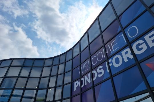 View looking up at the outside of Ponds Forge with blue skies with a few clouds above