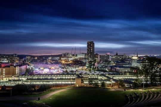 Sheffield city centre skyline in the evening with lights in the distance and an inky blue sky