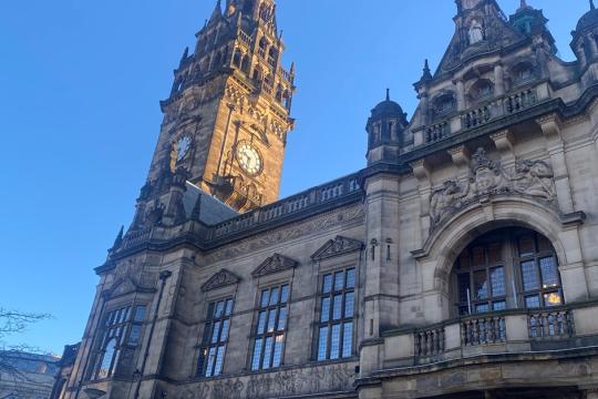 Image of the front of the Town Hall showing the balcony and the clock tower under a blue sky