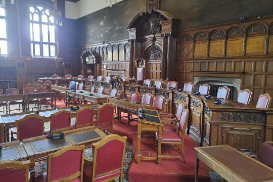 The Council Chamber at Sheffield Town Hall with the desks and chairs laid out ready for a meeting and light shining through the windows on a cloudy day