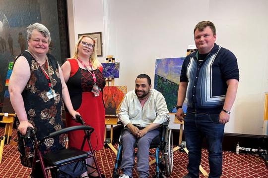 Four people in front of their artwork