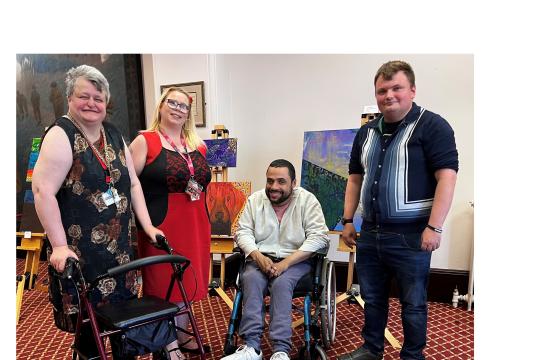 Attendees at Learning Disability Week launch in front of artwork