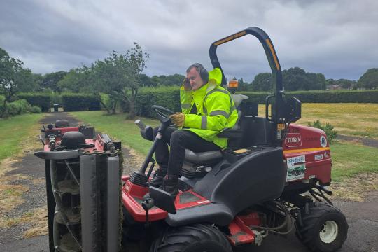 Aaron, grounds maintenance worker on a mower  