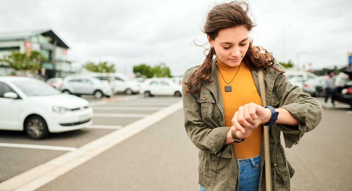 Woman looking at watch in car park